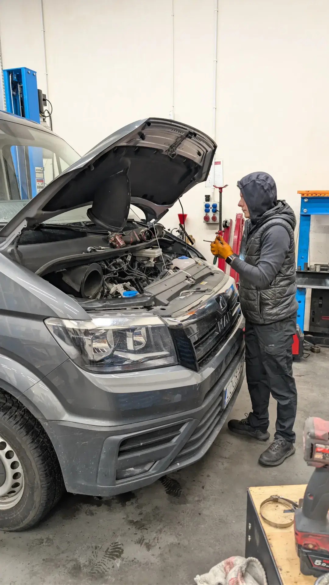 Mechanik samochodowy wykonujący naprawę silnika pod maską samochodu dostawczego VW Crafter w serwisie Autoshrek.