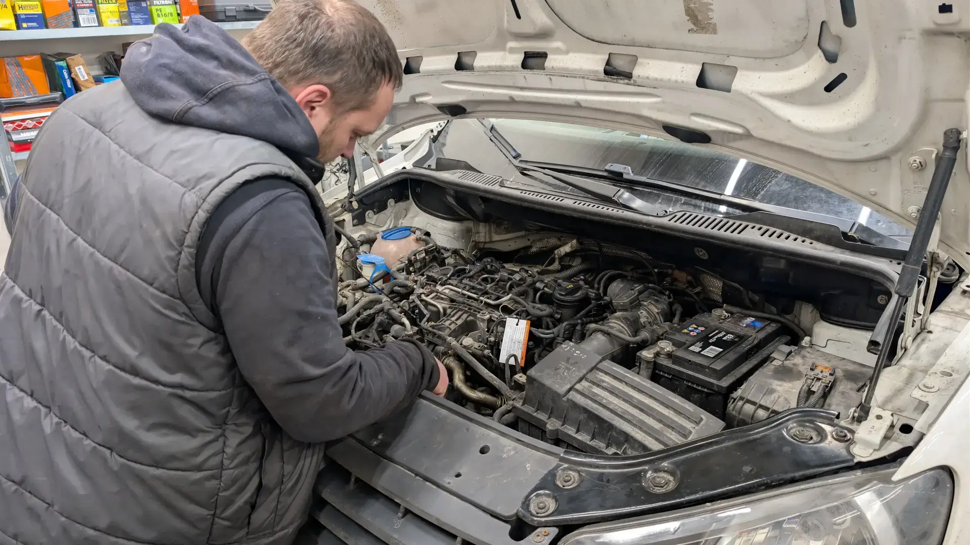Zbliżenie na mechanika diagnozującego usterkę silnika Diesla w samochodzie osobowym.
